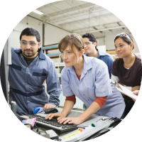 Photo of workers at an advanced manufacturing facility using a computer.