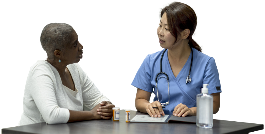 Photo of senior patient and medical professional sitting and talking at a table.