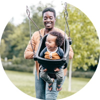 Photo of a parent with their child on a swing.
