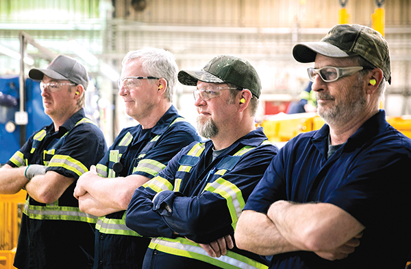 Photo of four employees standing in a line in a Mining Machinery Manufacturing Facility.