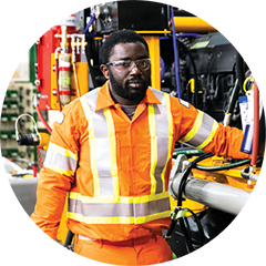 Photo of an employee standing next to mining equipment.