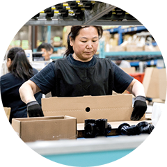 Photo of a worker preparing boxes for shipping in a warehouse facility.