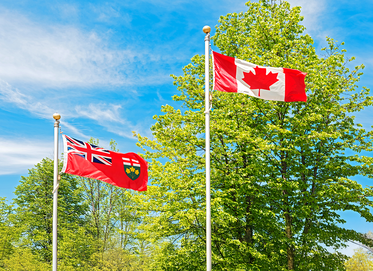 Photo of the Ontario and Canadian flag on a windy day.