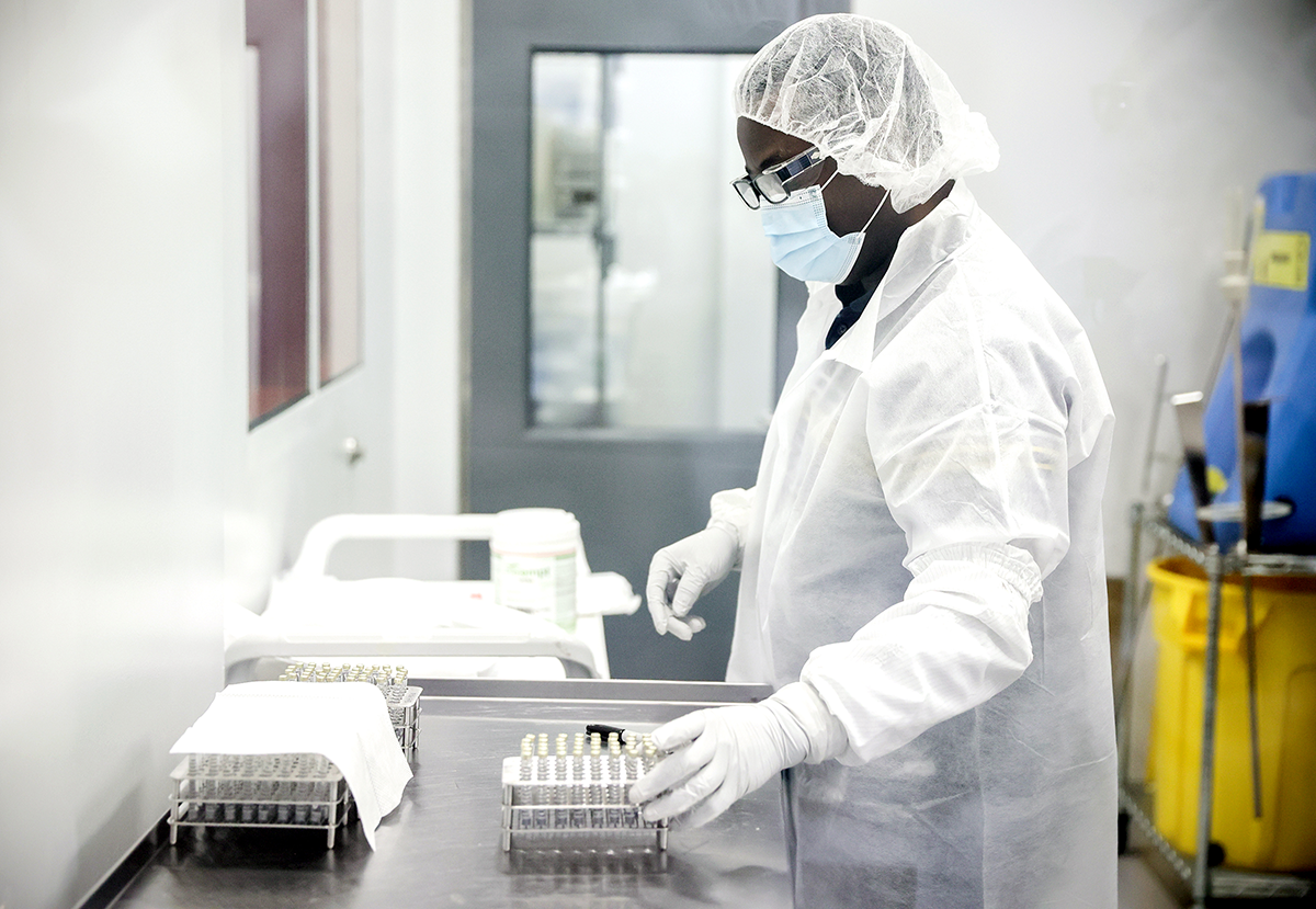 Photo of a sterile laboratory with worker in protective overall working on samples.