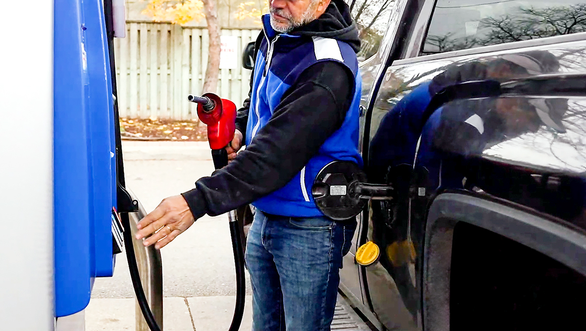 Photo of a person refueling car at a gas station.