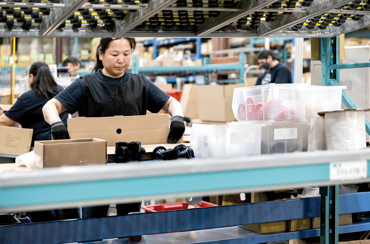 Photo of a worker preparing boxes for shipping in a warehouse facility.
