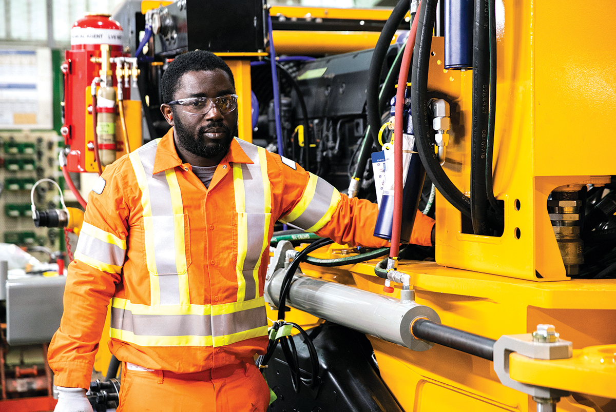 Photo of an employee standing next to mining equipment.
